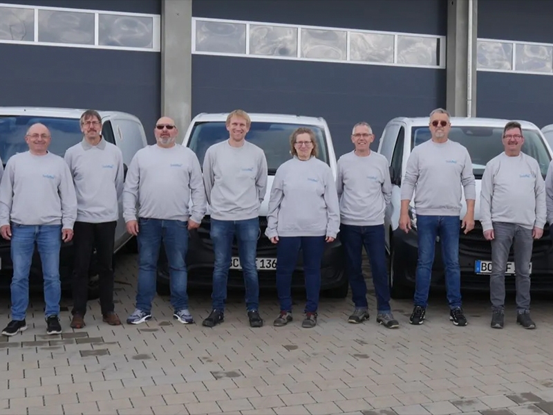 Ein Teil des TROCKENEIS24 Teams steht vor den Firmenfahrzeugen. Alle tragen einen grauen TROCKENEIS24 Pullover.